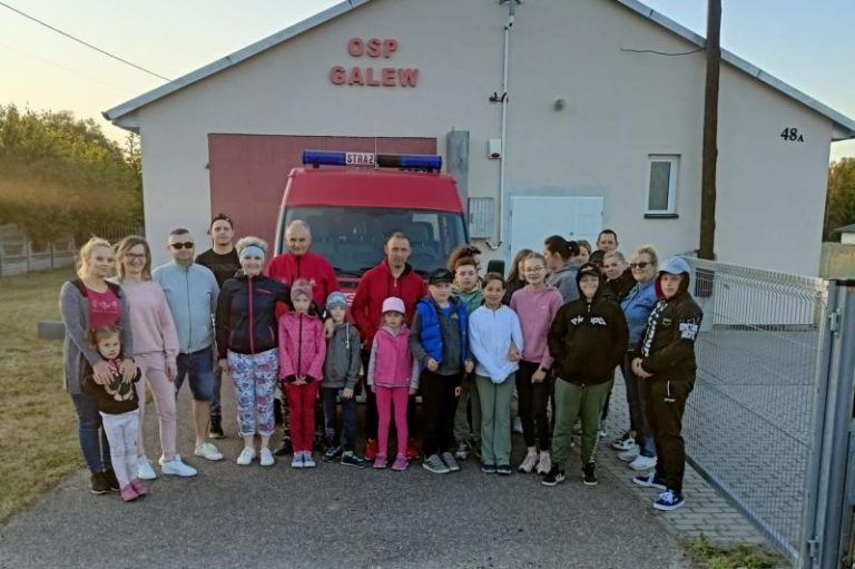 Grupa dzieci i dorosłych przed budynkiem OSP Galew
