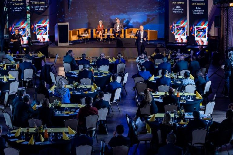 Impreza firmowa na przyciemnionej sali restauracyjnej z pracownikami / klientami siedzącymi przy stolikach