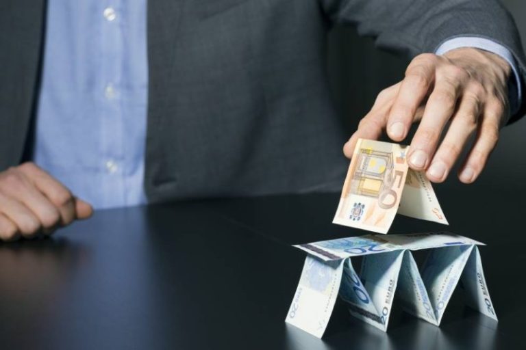 Mężczyzna układający domek z kart (z banknotów)