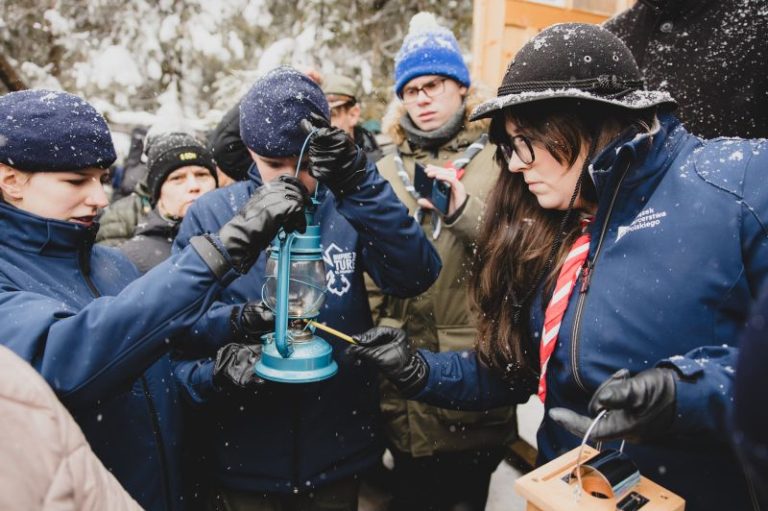 Harcerze w zimowej scenerii z Betlejemskim Światłem Pokoju