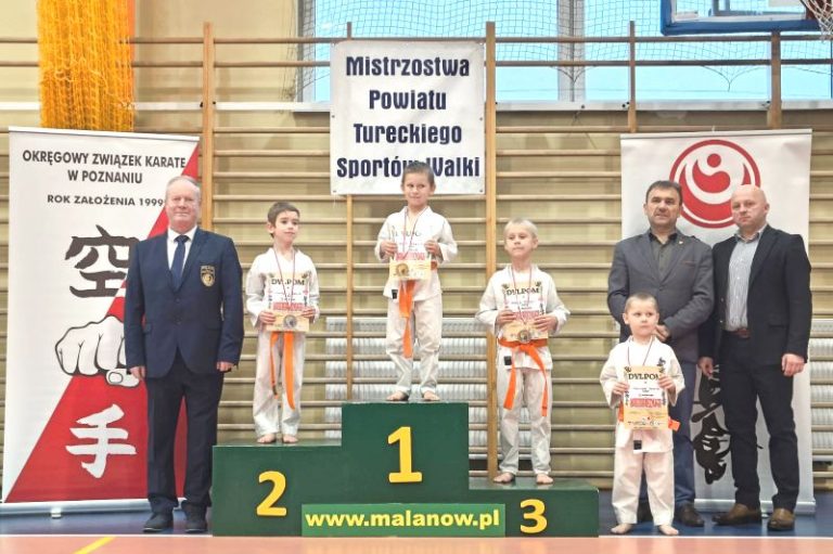 od lewej: Dariusz Jasiakiewicz, trzech młodych karateków na podium, wójt Ireneusz Augustyniak, Krystian Krawczyk