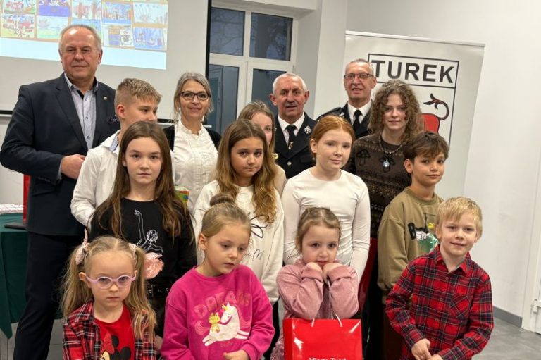 Grupa dzieci, laureatów konkursu plastycznego, pozuje do zdjęcia ze strażakami z OSP Turek