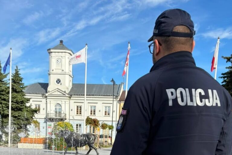 Policjant (na plecach napis "Policja") spoglądający w kierunku ratusza na pl. Wojska Polskiego w Turku