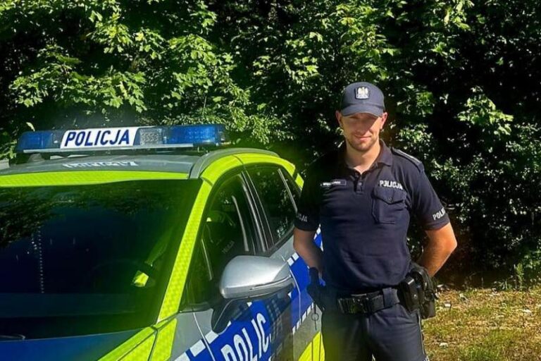 mł. asp. Jacek Wieczorek, policjant z Tuliszkowa stoi przy policyjnym radiowozie.